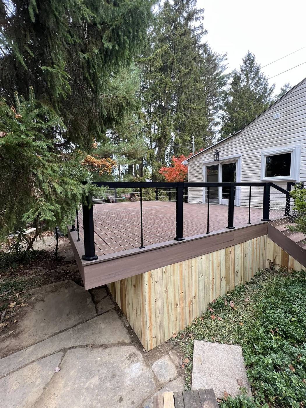 Composite deck with black cable railing and wood skirting