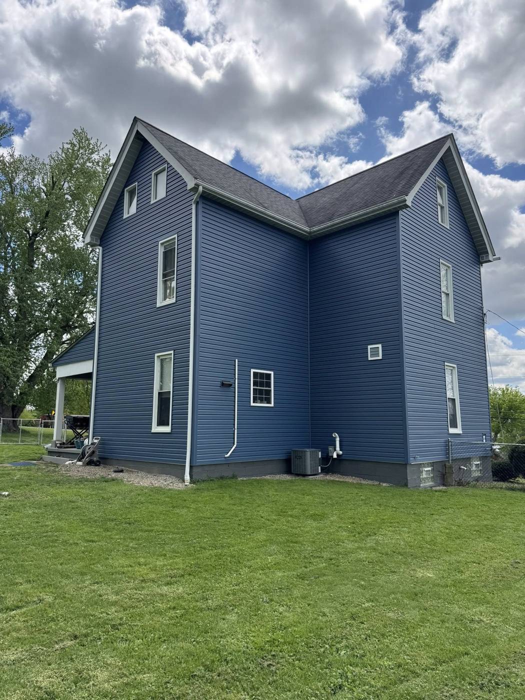Completed deep blue vinyl siding installation with white trim